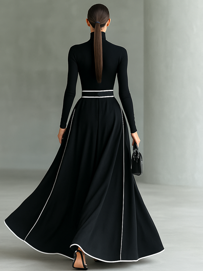 Vestido largo negro con costuras blancas, cuello alto, mangas largas y cintura ajustada.